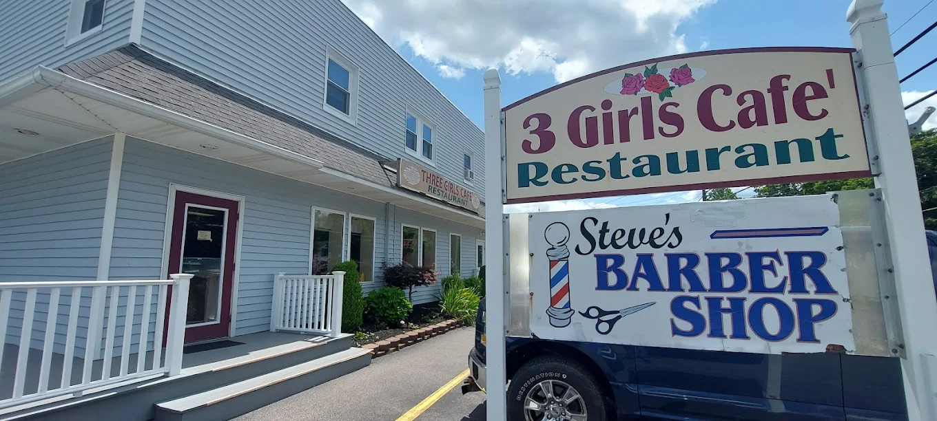 Three Girls Cafe storefront with the cafe sign and Steve's Barber Shop sign